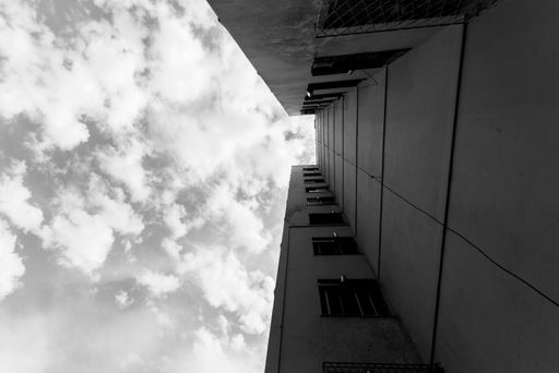 A low-angle grayscale shot of a residential building under a cloudy sky.