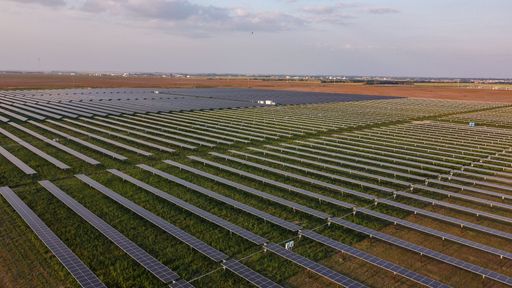 An aerial view of solar panels with vast fields in the background