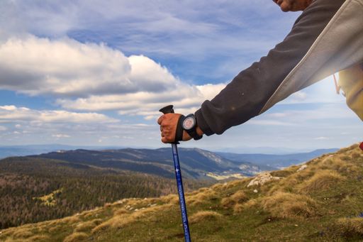 A person with a backpack hiking in the rocky mountains under a cloudy sky