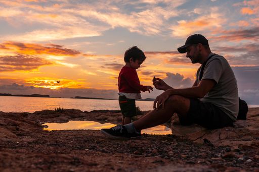 A father playing with his little son on a beach at sunset in San Antonio Abad, Ibiza Island