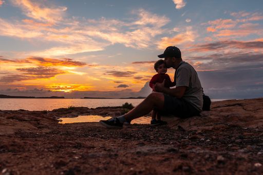A father playing with his little son on a beach at sunset in San Antonio Abad, Ibiza Island