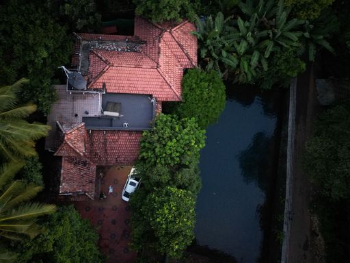 A bird's eye view of a villa with a pool and a white car parked in the front