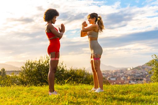 African-American and Caucasian female friends doing workout outdoors - healthy lifestyle and diverse friendship concept