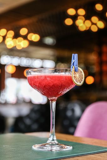 The vertical view of a glass of red alcohol cocktail with a dry tangerine dressing on the bar counter