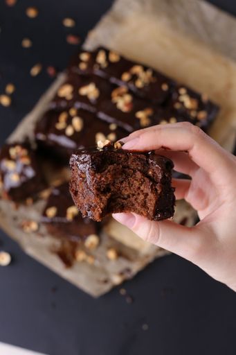 The vertical view of a hand holding a piece of brownie cake