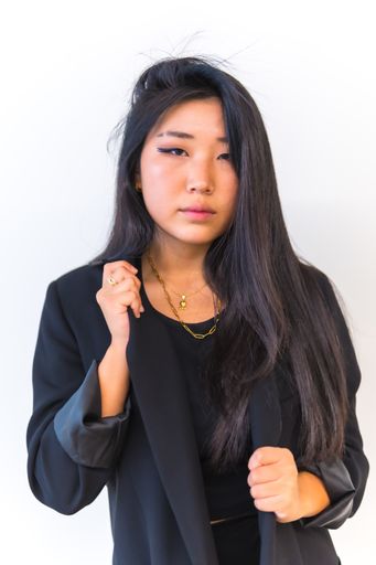 A vertical shot of a beautiful Chinese woman wearing casual black clothing and posing in front of a white background