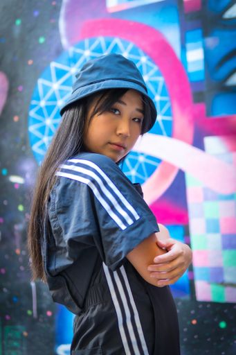 A vertical shot of a beautiful Chinese girl with street style clothing posing outdoors during daylight