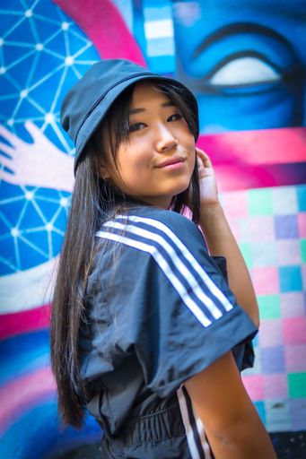 A vertical shot of a beautiful Chinese girl with street style clothing posing outdoors during daylight