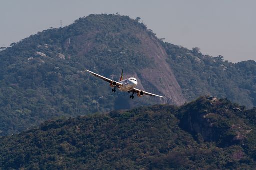 An Airbus A319 coming for landing at Santos Dumont Airport, Rio de Janeiro City, sunny day, overgrown hill in the background
