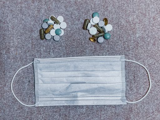 A top view shot of various pills next to a medical face mask - concept of Coronavirus/medicine