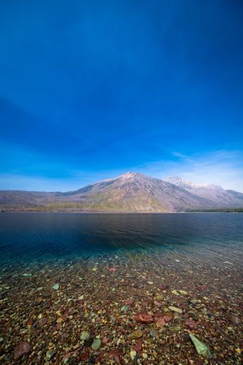 A vertical shot of a scenic lake shore during daytime in  Glacier National Park, Montana