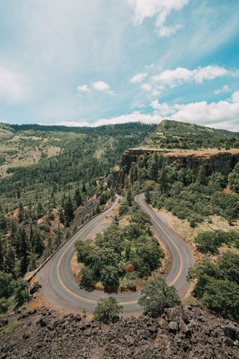 An aerial vertical shot of the round road surrounded by forest on a sunny day, Big Sur, California