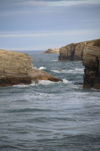 A vertical shot of huge cliffs during the high tide, the beach of 
the Cathedrals in Ribadeo Lugo, Galicia