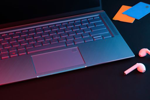 A closeup of a laptop near wireless earphones