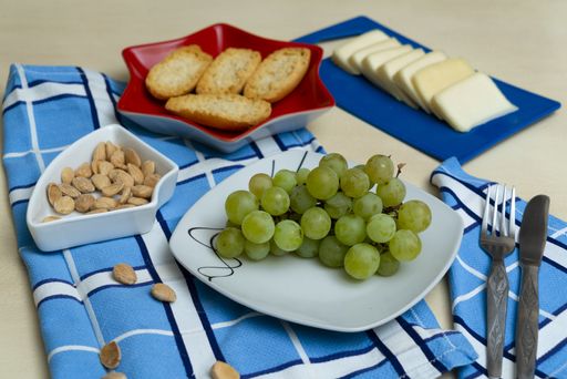 A closeup shot of grapes, crackers, cheese, cutlery on the table