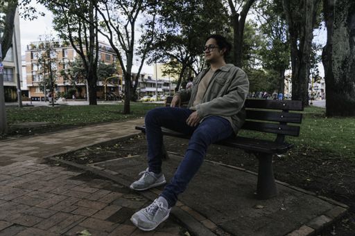 A young Hispanic man sitting on a bench and having a rest