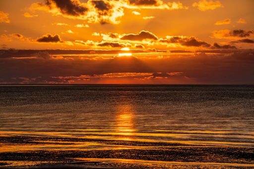 A beautiful sunset reflecting on the surface of the sea with an orange sky in the background