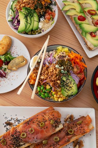 A vertical top view of poke bowls and fish with vegetables on a wooden table