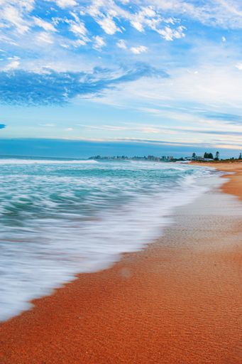 A vertical shot of a beautiful beach under a blue cloudy sky at dusk