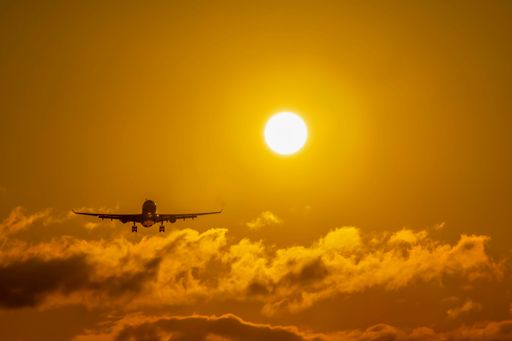 A closeup shot of a plane flying in the sky on a sunny day