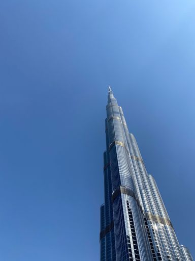 A low angle shot of a Burj Al Arab skyscraper with blue sky in the background