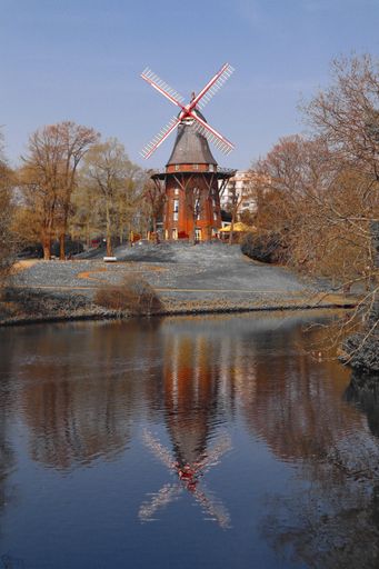 A vertical shot of the windmill  on an island near water in orphan light in Germany