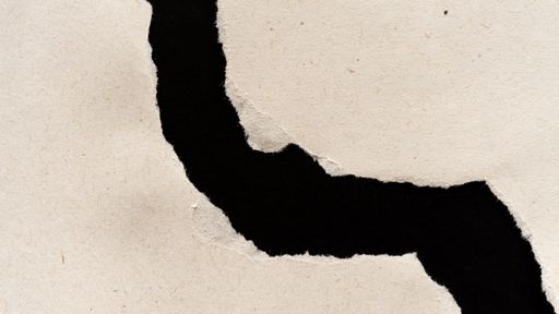 A macro shot of a torn paper with rough edges, on a black background, the concept of a geographical map