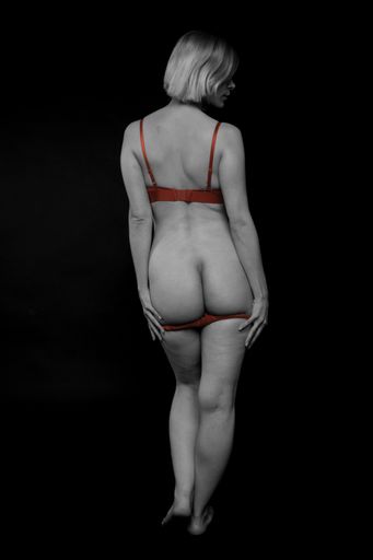 A vertical shot of a half-naked model wearing red underwear posing for a photoshoot