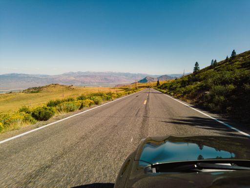 A car driving on a highway road through a beautiful green field