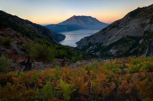 A scenic view of an ocean and mountain range from the top of a hill, captured from a high angle