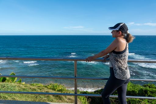 Beautiful woman standing enjoying the beautiful sea. Beautiful day with strong sun and blue sea. back view