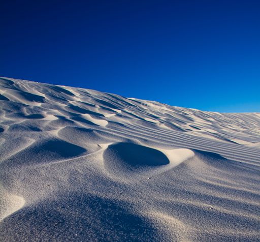 A magical landscape of white sand dunes on a hill against a blue sky