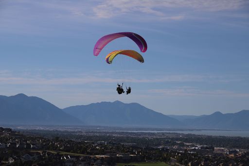 Two people paragliding at Salt Lake County Flight Park during the sunrise