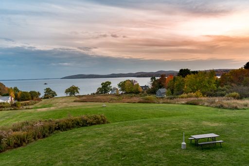 A scenic panoramic shot of green field near the coast at sunset in New England, Maine, USA