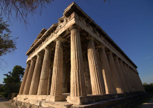 The exterior of Temple of Hephaestus in the Agora of Athens with sunlight under blue sky