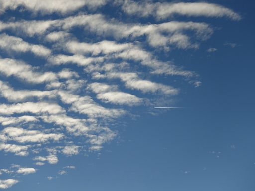 Airplane trail on the blue sky with interesting clouds