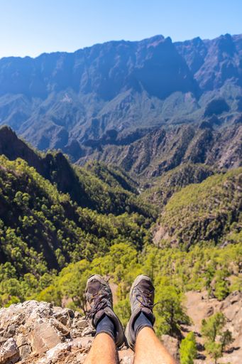 A vertical shot of male's feet and the La Cumbrecita National Park in the island of La Palma, Canary Islands, Spain