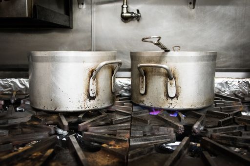 A pair of rusty old pots being heated on the stove in a kitchen