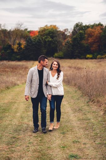 A vertical shot of a cute caucasian couple walking on the mowed lawn in the field
