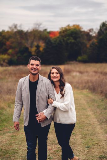 A vertical shot of a cute caucasian couple walking on the mowed lawn in the field