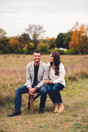 A vertical shot of a cute caucasian couple sitting on the bench in the field