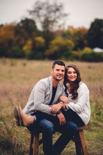 A vertical shot of a cute caucasian couple sitting on the bench in the field