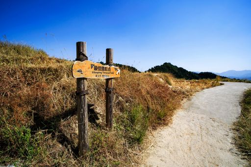 A road sign in China, showing the way to terraced fields, and a path next to it, on a sunny day with a clear sky