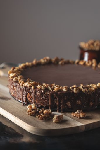 A vertical shot of a delicious chocolate cake with nuts on a wooden board