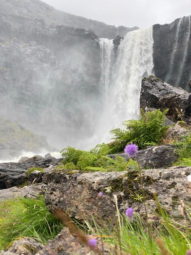 A vertical shot of a waterfall on a cliff in Faroe Islands