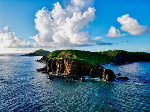 A gorgeous aerial view of green hills on Saint Thomas overlooking the bright blue waters of the Caribbean