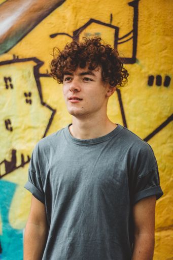 A South African man wearing t-shirt and standing against a yellow wall