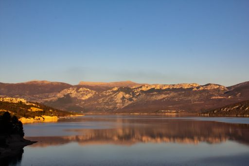 A wide shot of the reflection of the mountains in a lake under the clear blue sky