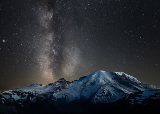 Majestic view of the night sky over Mount Rainier, featuring a bright Milky Way illuminating the majestic mountain range below
