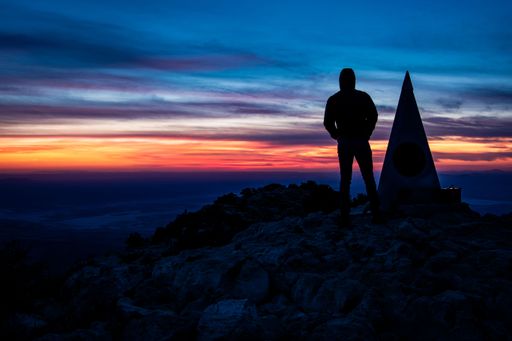 A silhouette of a man standing on the Guadalupe Peak at sunset